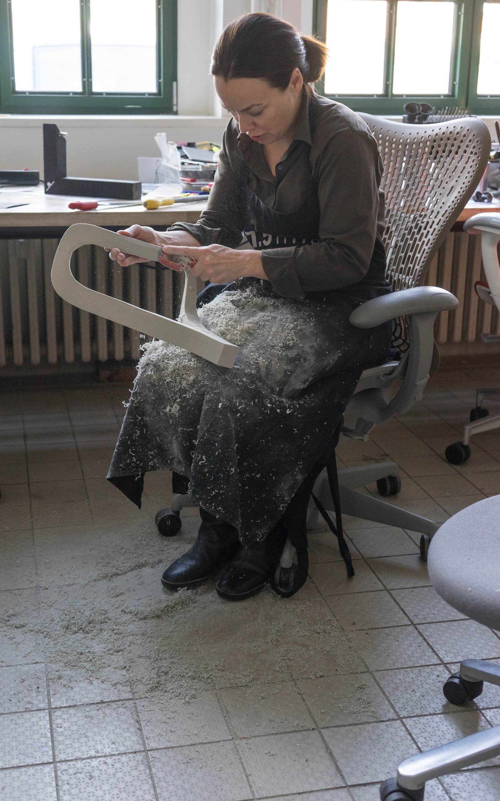 A member of Studio 7.5 shaves down material to make a model during the development of the Cosm Chair.